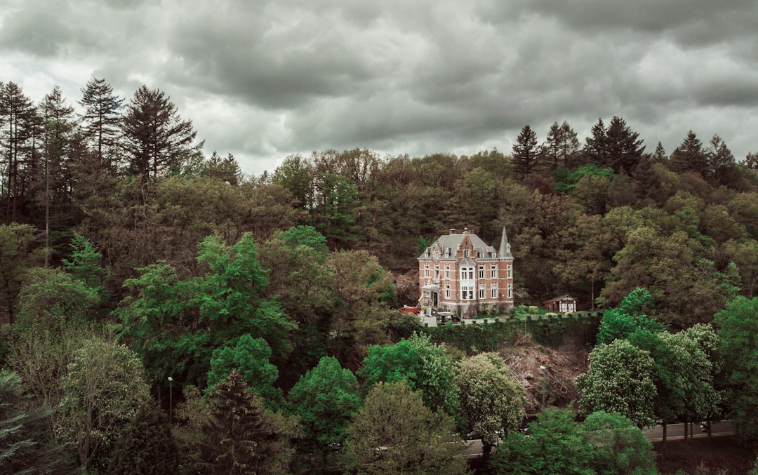 white concrete building surrounded by green trees under cloudy sky during daytime