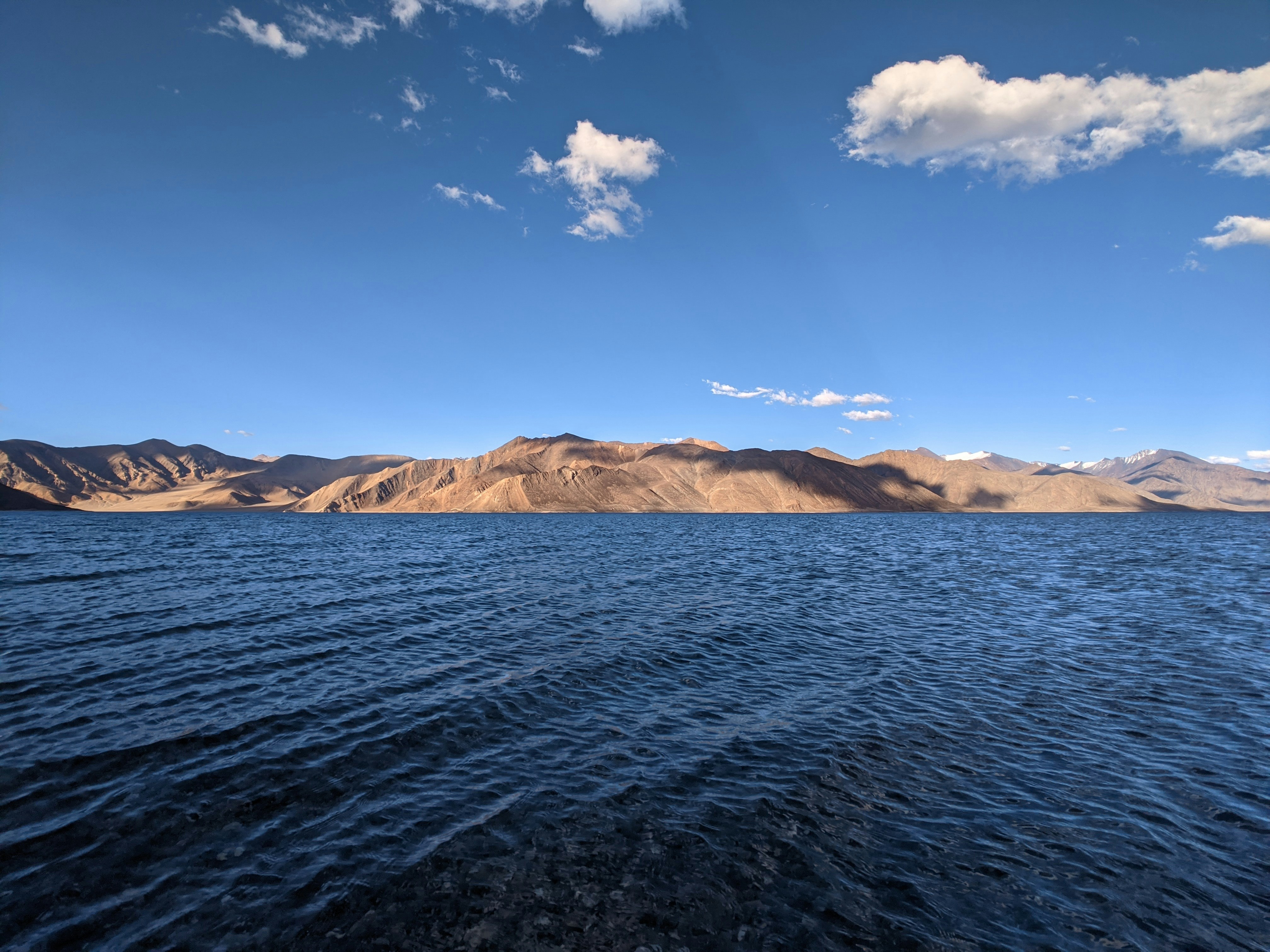 blue sea near brown mountain under blue sky during daytime