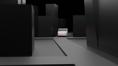 A minimalist, dark urban scene with tall, featureless black buildings surrounding a central, small, white vehicle. The ground is flat and gray, contributing to the stark, almost abstract feel of the environment.