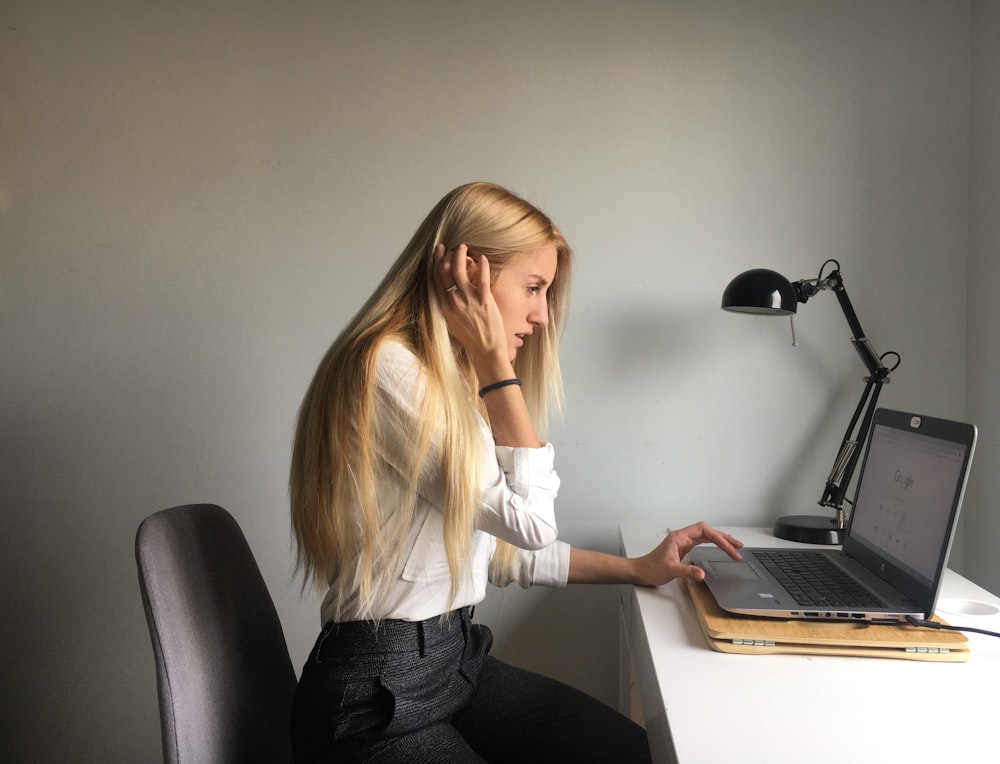 woman in white long sleeve shirt and black pants sitting on black office rolling chair