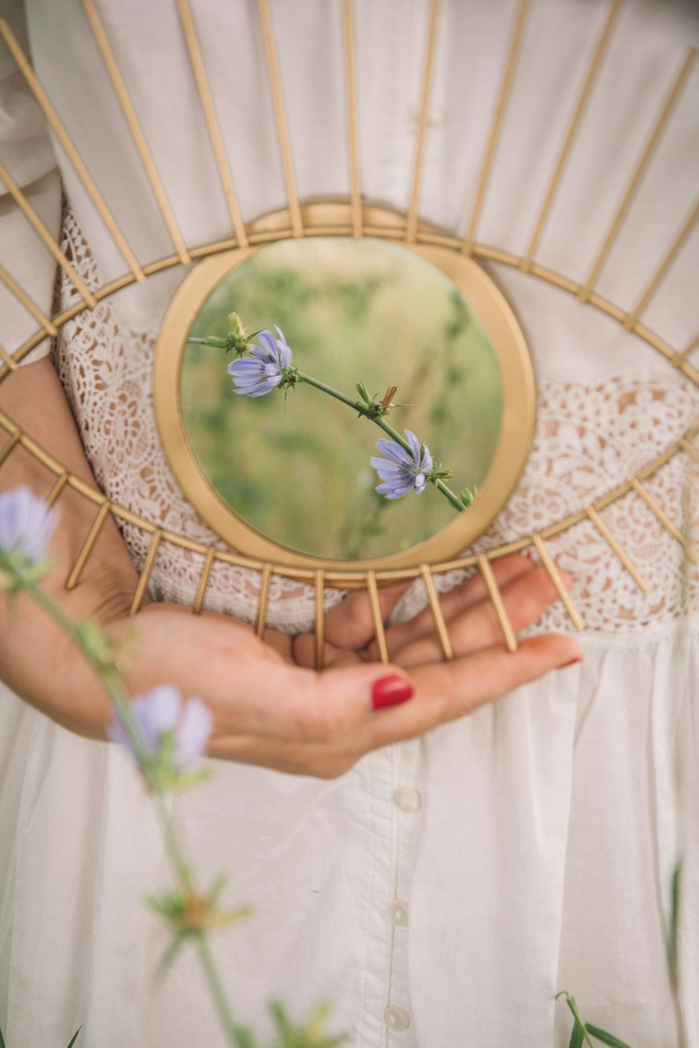 person holding gold framed round mirror