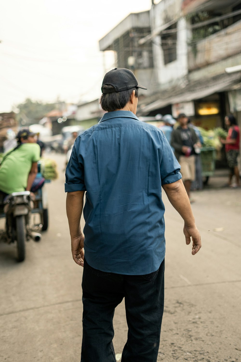 昼間、歩道に立つ青いポロシャツと黒いズボンを着た男性
