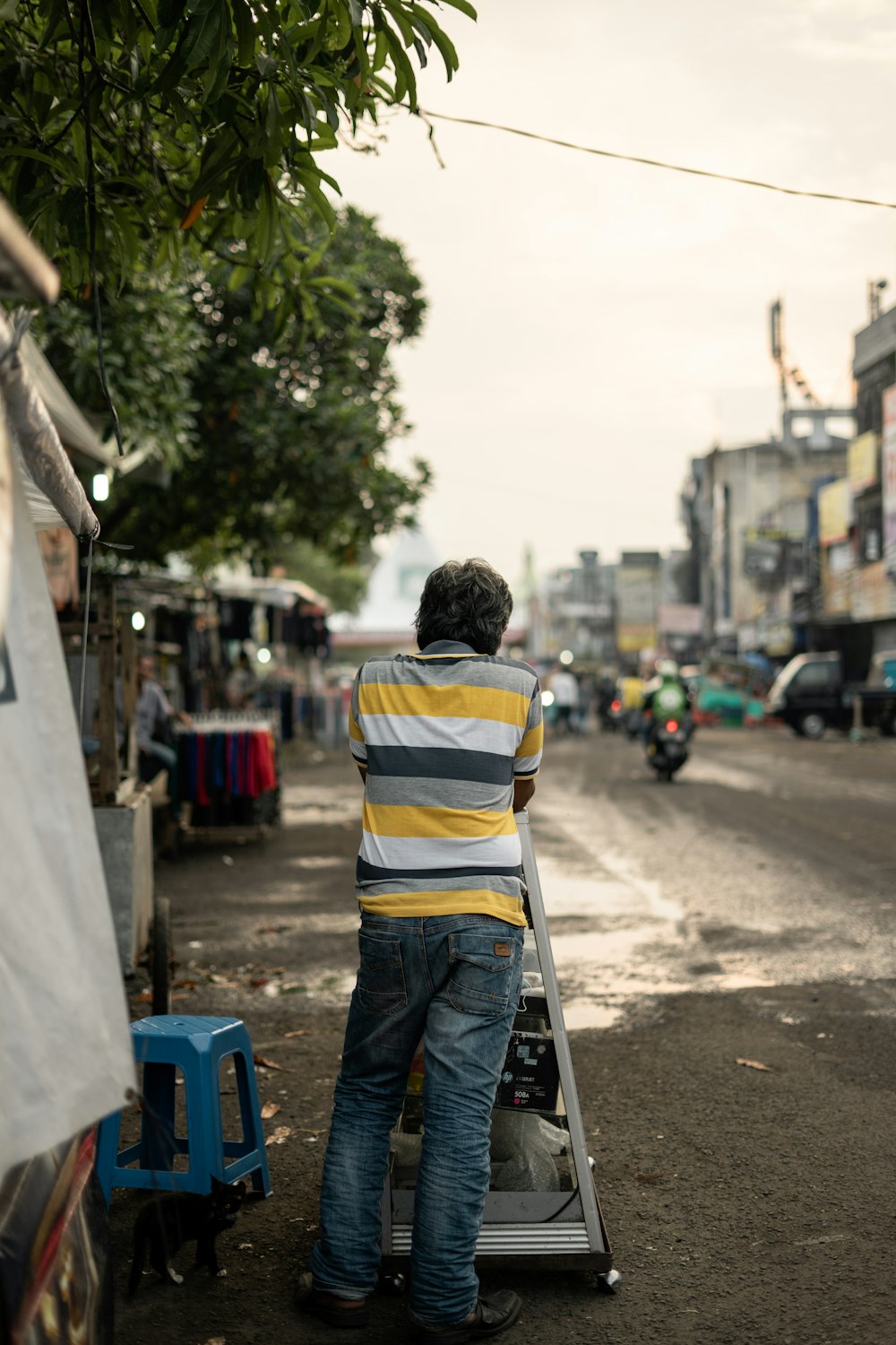 man in yellow and blue striped shirt standing on the street