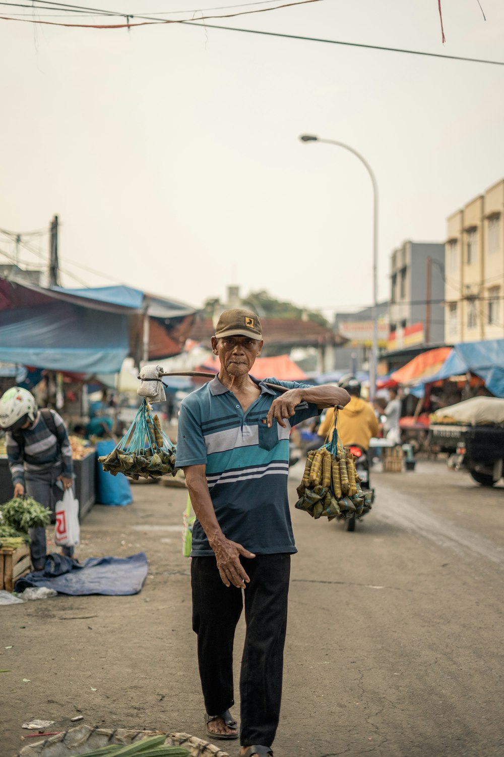 man in blue and white stripe polo shirt and black pants standing on street during daytime