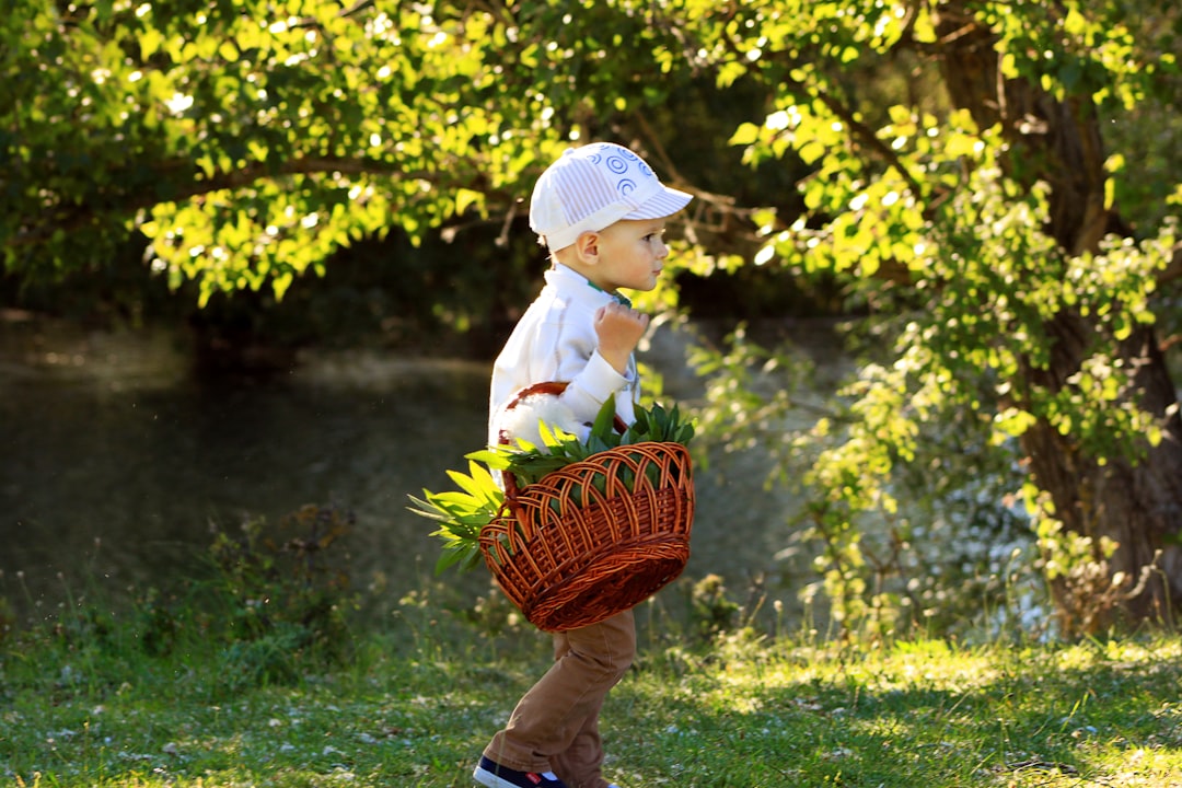 child in white long sleeve shirt and white hat holding basket
