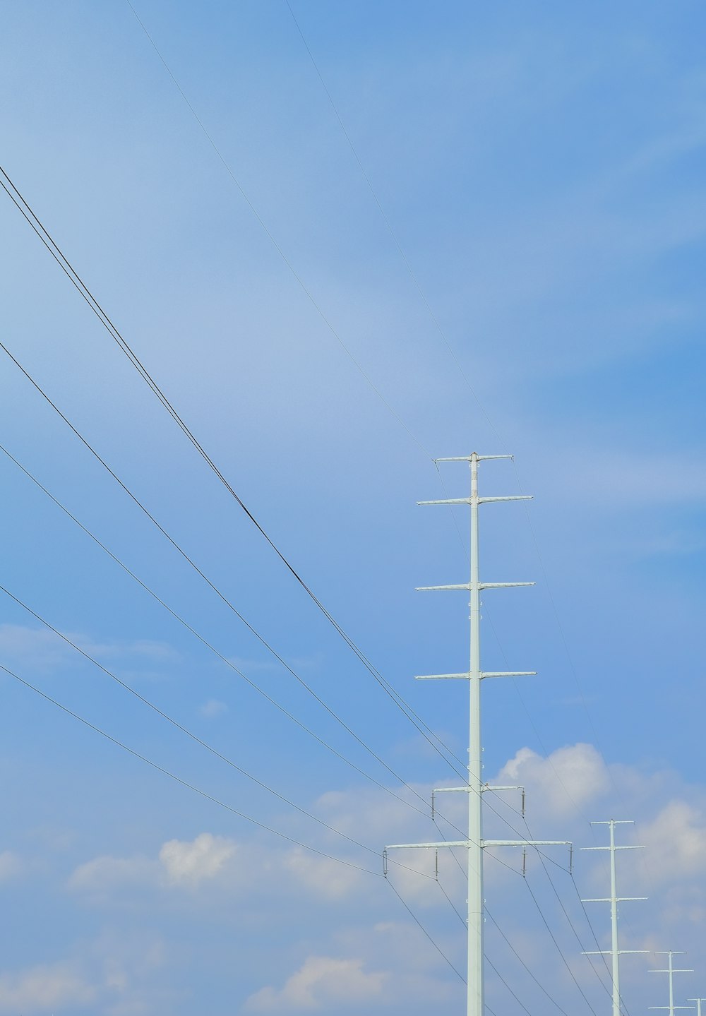 낮 동안 푸른 하늘 아래 흰색 전기 포스트