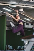 A dynamic bungee fitness session with a woman mid-jump, purple and black studio background.