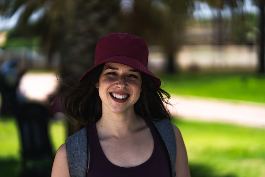 smiling woman in black tank top wearing red cap