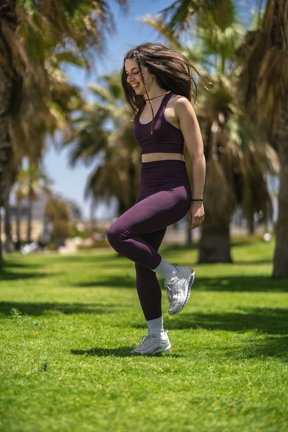 woman in black tank top and purple leggings running on green grass field during daytime