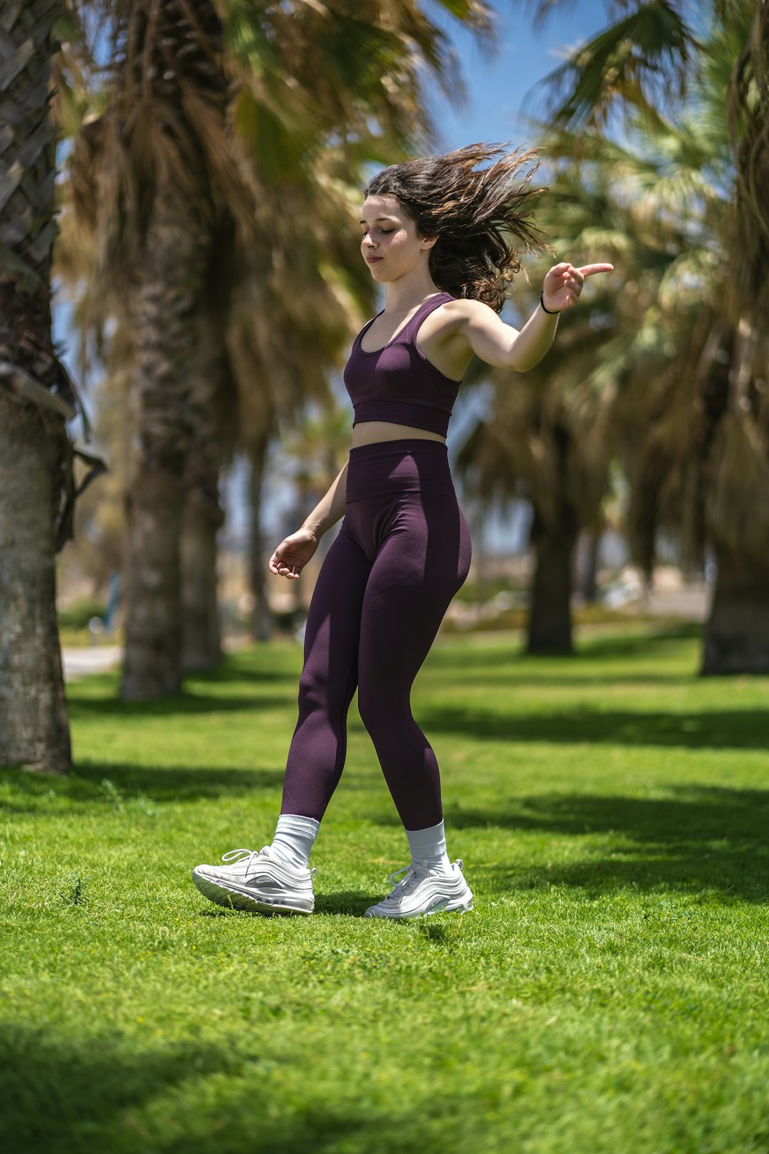 woman in purple tank top and black leggings running on green grass field during daytime