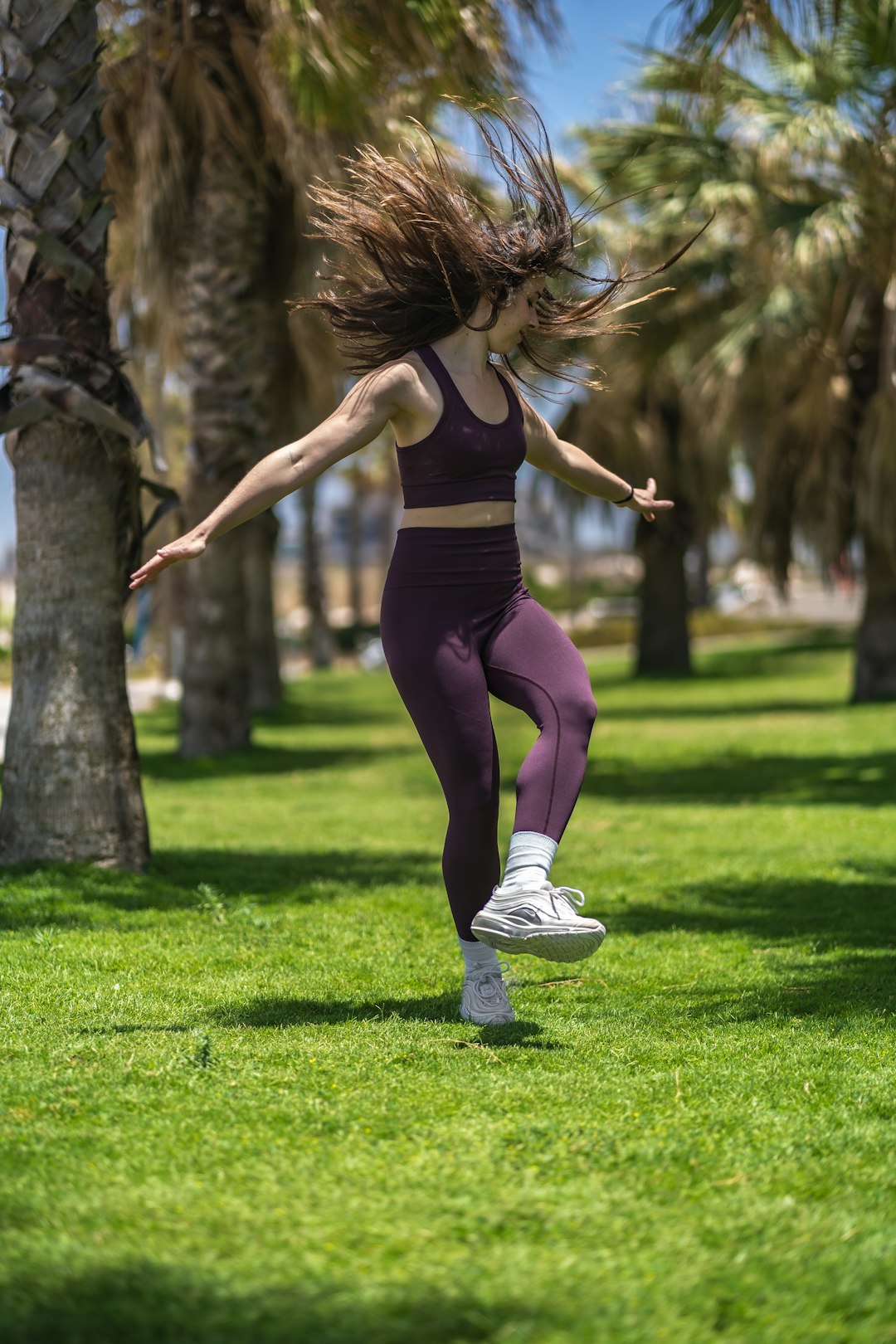 woman in black tank top and purple leggings doing yoga on green grass field during daytime