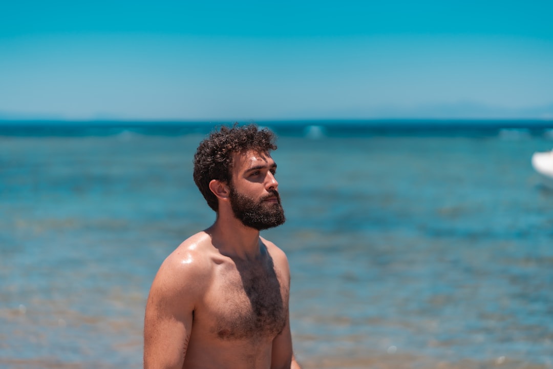 topless man standing near body of water during daytime