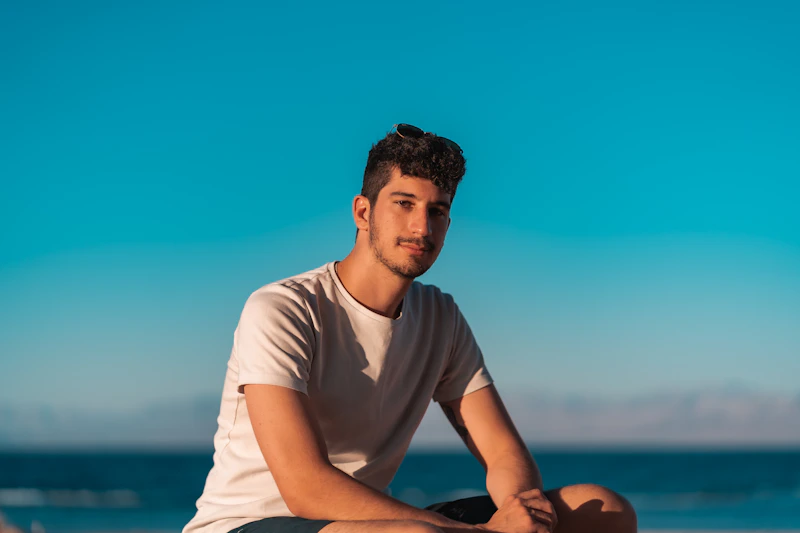 Caballero con camiseta blanca de cuello redondo sentado en silla azul