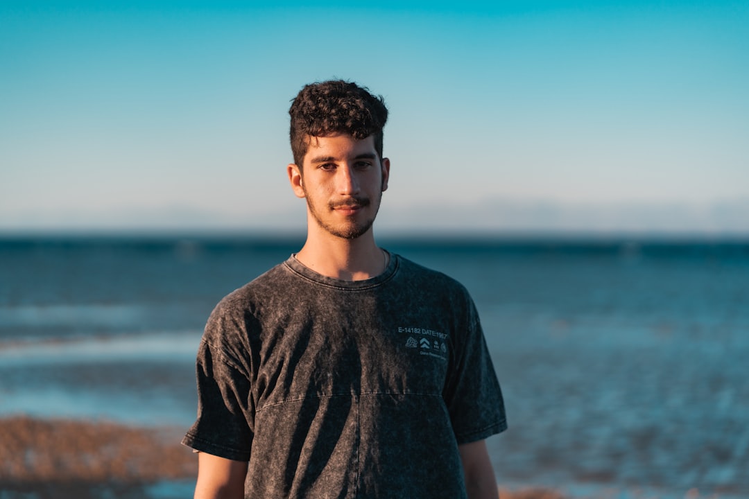 man in black crew neck t-shirt standing near body of water during daytime