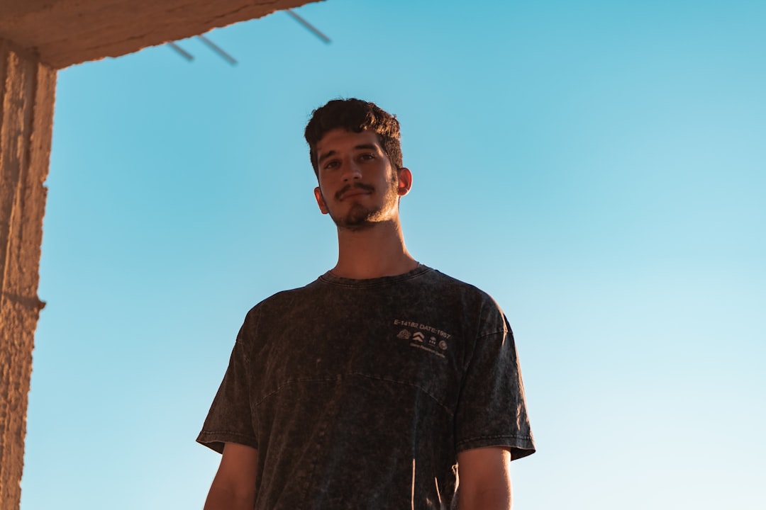 man in black crew neck t-shirt standing under blue sky during daytime