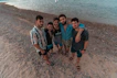 group of people standing on brown sand near body of water during daytime