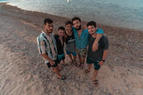 group of people standing on brown sand near body of water during daytime