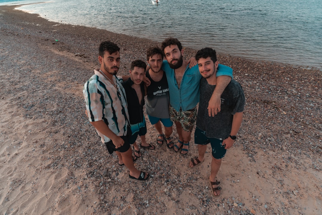 group of people standing on brown sand near body of water during daytime