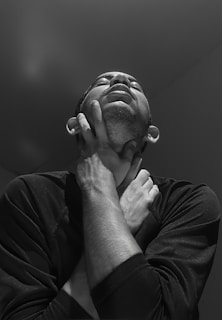 Close-up of a person touching their throat, showing discomfort.