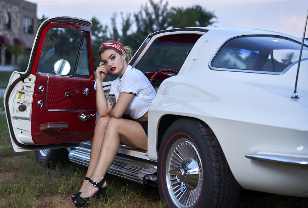 woman in white dress sitting on red car