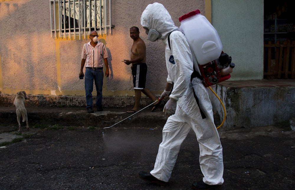 man in white pants holding black hose