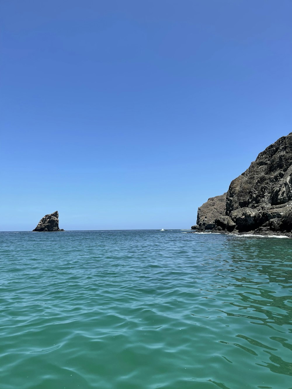 brown rock formation on sea under blue sky during daytime