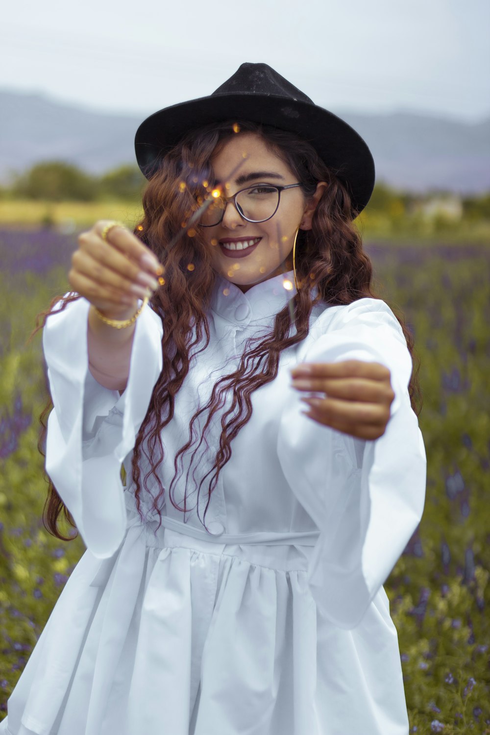 smiling woman in white long sleeve dress wearing black hat