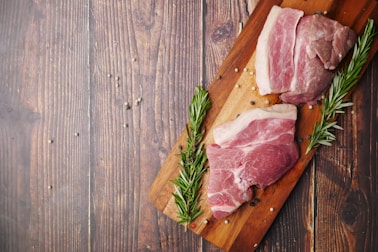 raw meat on brown wooden chopping board