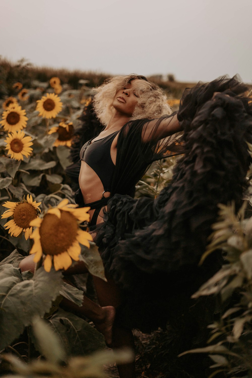 woman in black dress sitting on white flower field during daytime