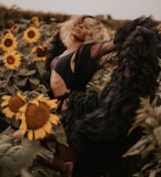 woman in black dress sitting on white flower field during daytime