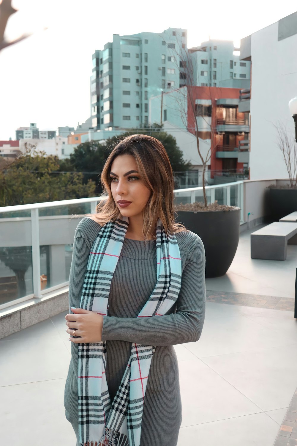 woman in gray cardigan standing near gray concrete wall during daytime