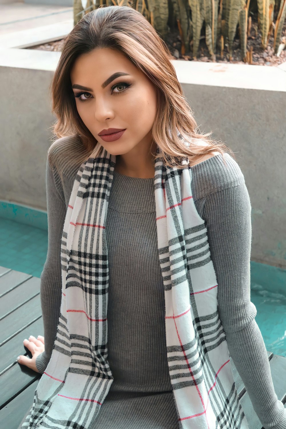woman in gray cardigan and red white and black plaid scarf