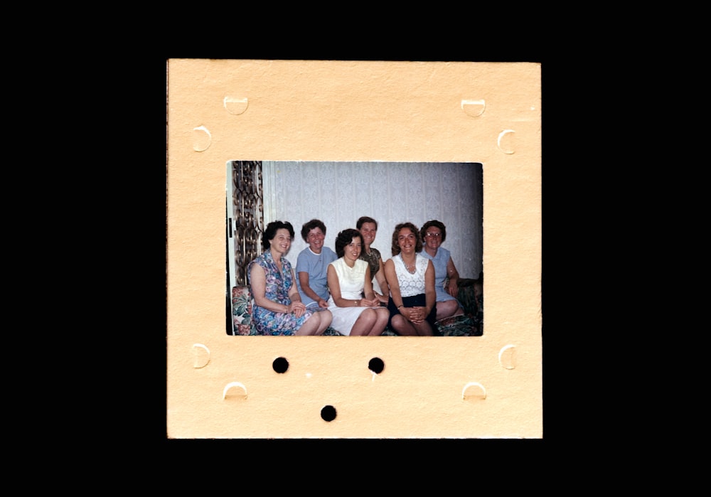 3 women and 2 men sitting on brown wooden bench