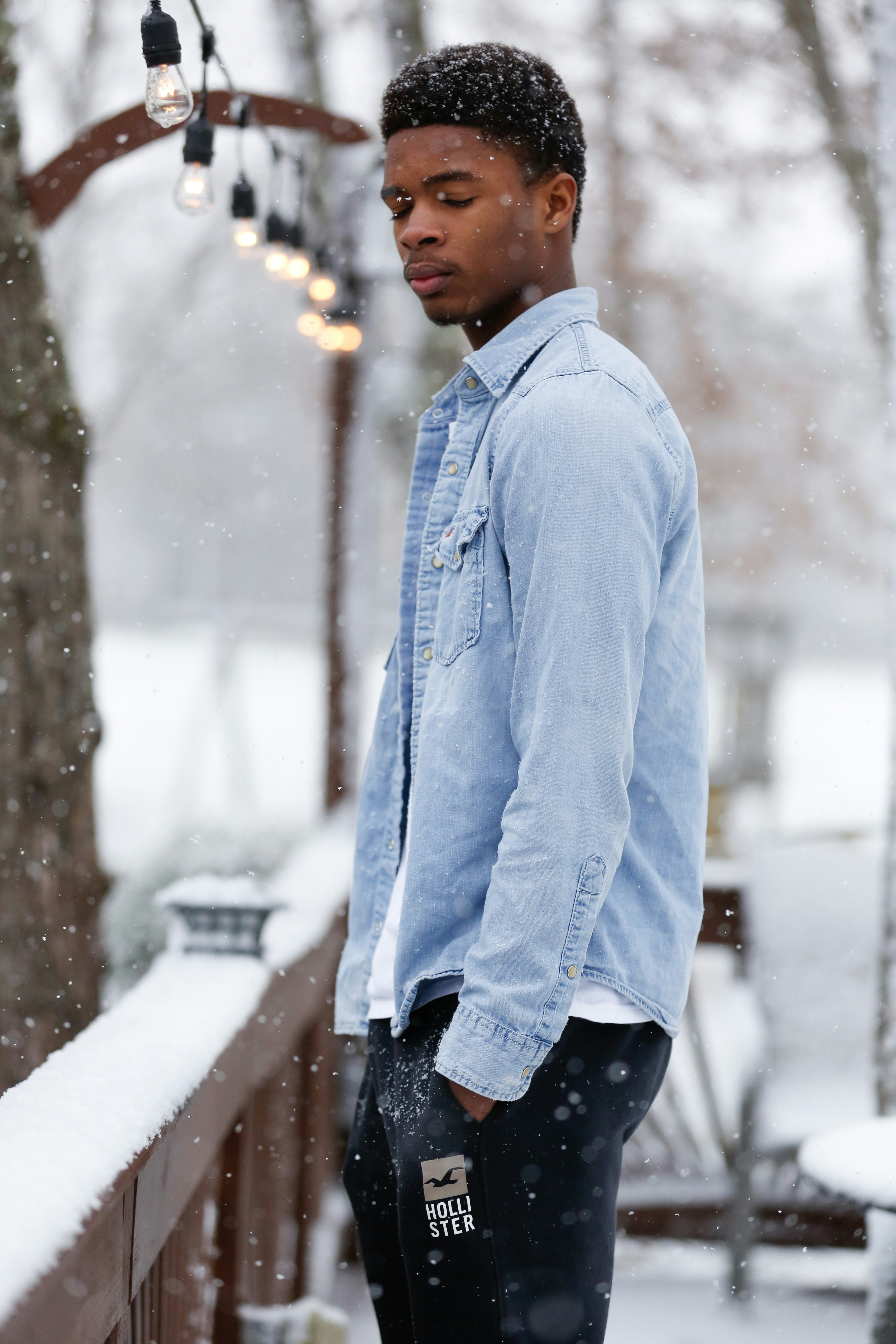man in blue dress shirt and black pants standing on snow covered ground during daytime