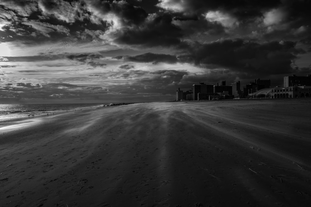 Foto en escala de grises de la playa bajo el cielo nublado