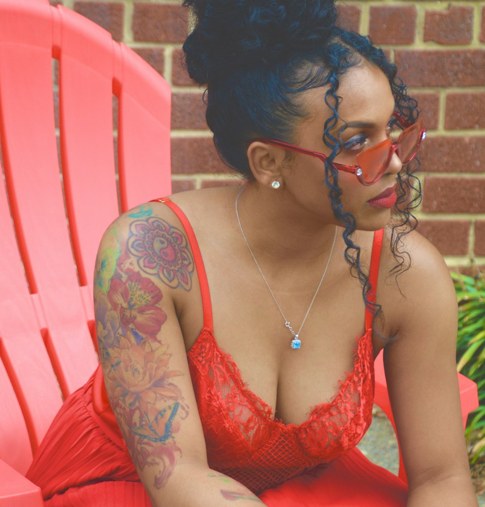 woman in red and black floral tank top sitting on pink chair