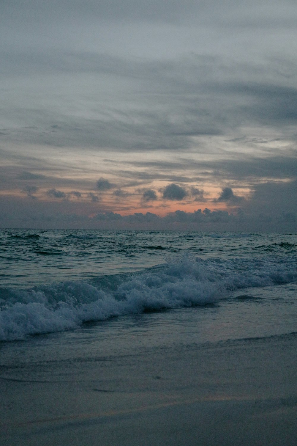 ocean waves crashing on shore during sunset