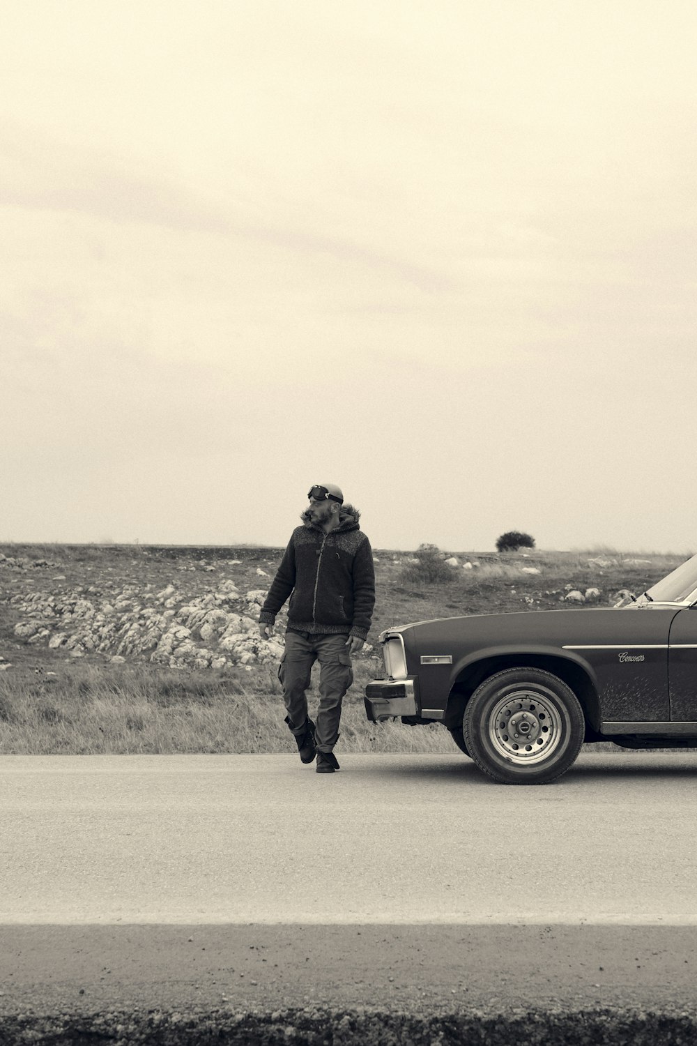 man in black jacket and pants standing beside black car on road during daytime