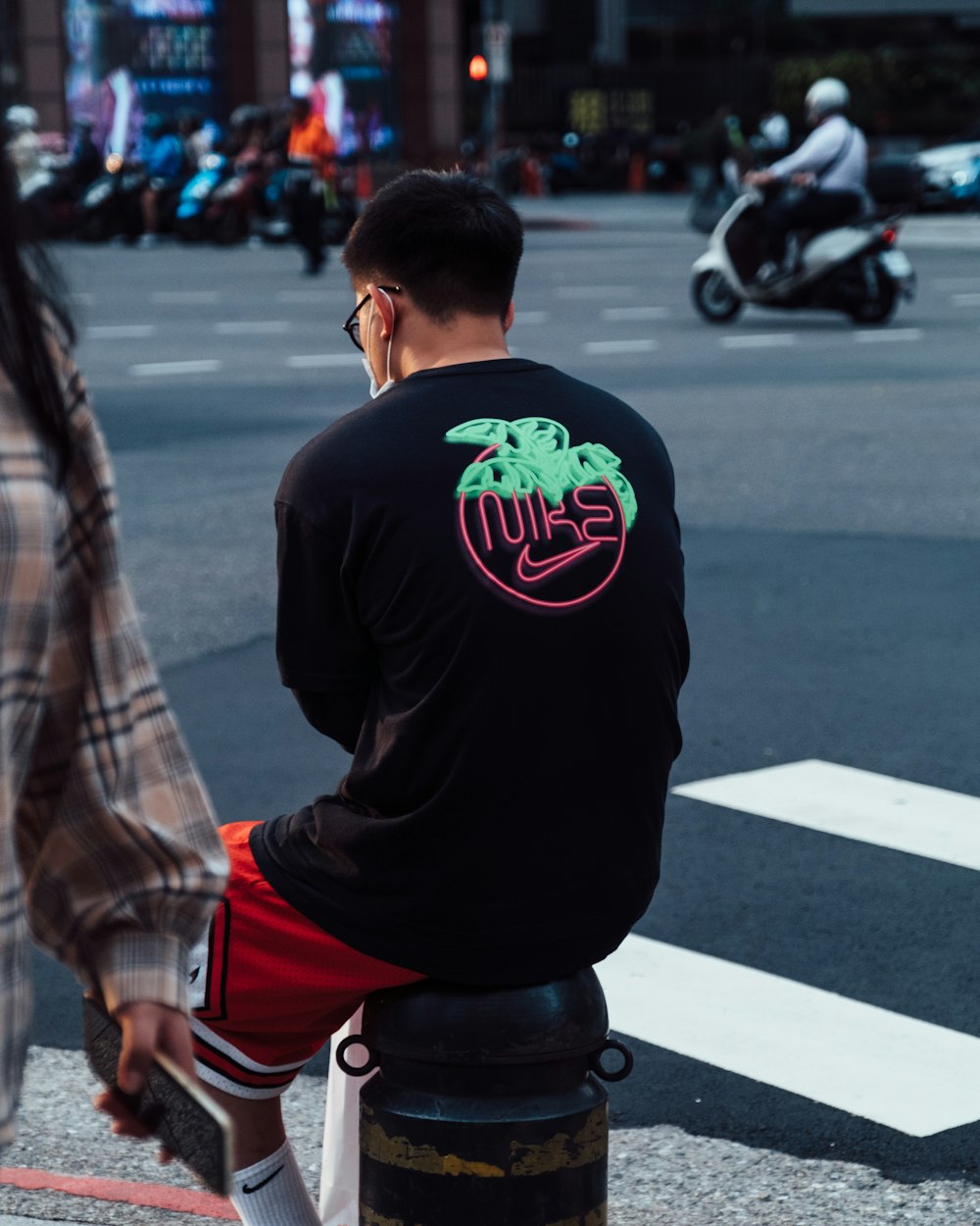 man in black crew neck t-shirt and red and white plaid shorts standing on street