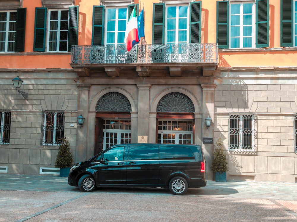 black sedan parked beside brown concrete building during daytime