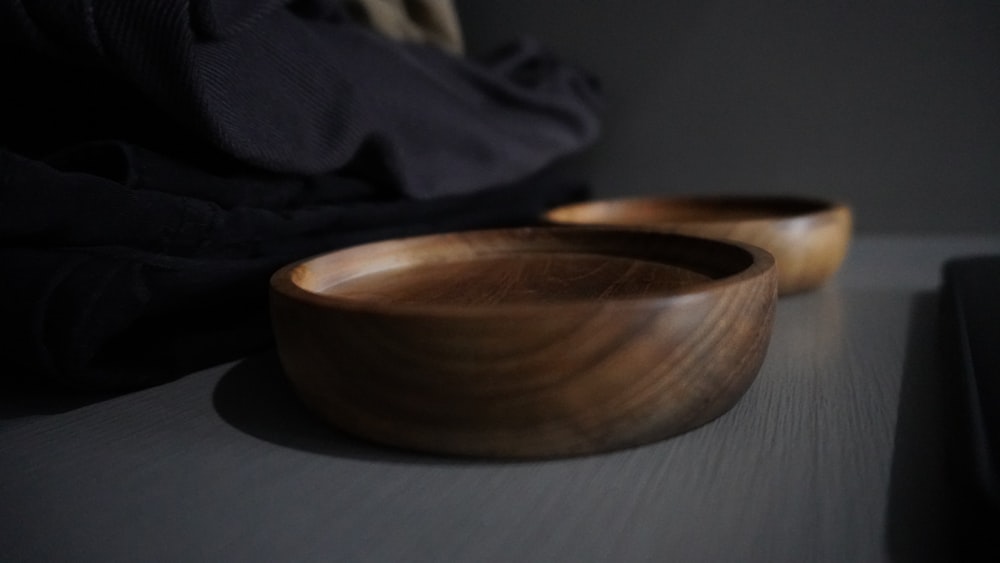 brown round wooden bowl on gray textile