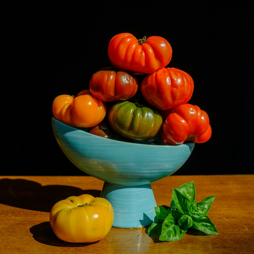 red yellow and green round fruit on blue ceramic bowl