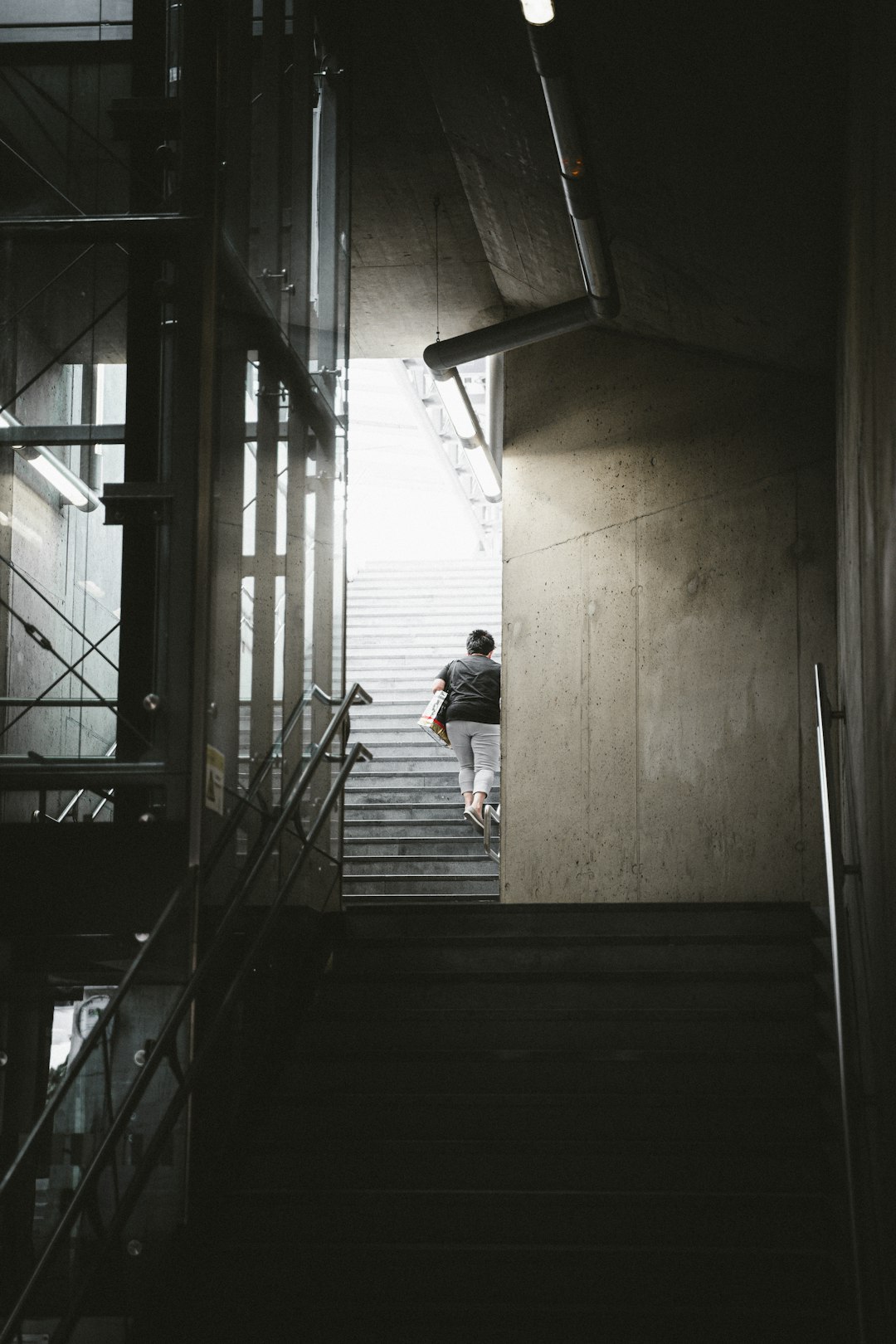 man in black t-shirt and blue denim jeans walking on stairs