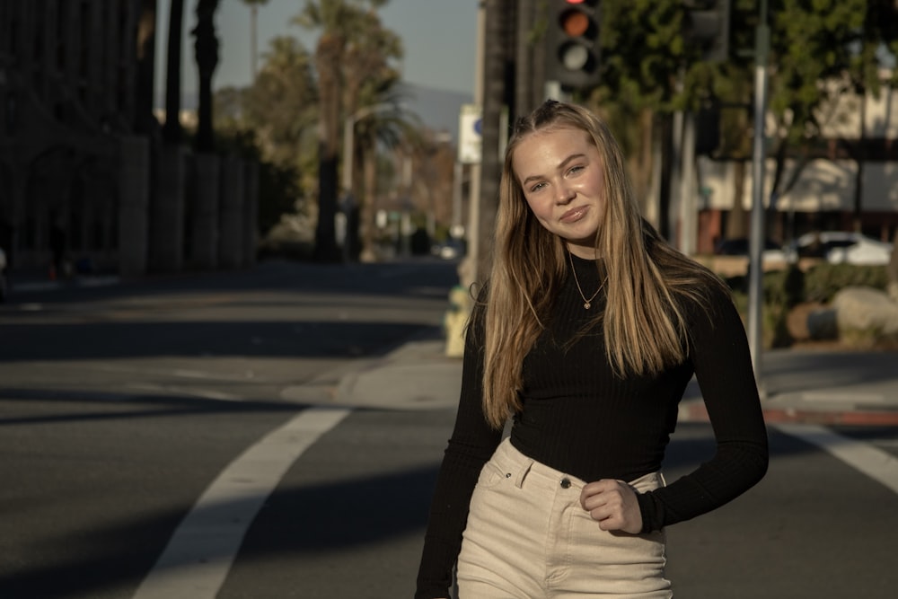 woman in black long sleeve shirt and white denim jeans standing on road during daytime