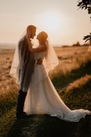 Bride and groom sharing a joyful embrace under warm sunset light at an outdoor wedding.