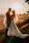 A couple embracing under a floral arch during a golden sunset.