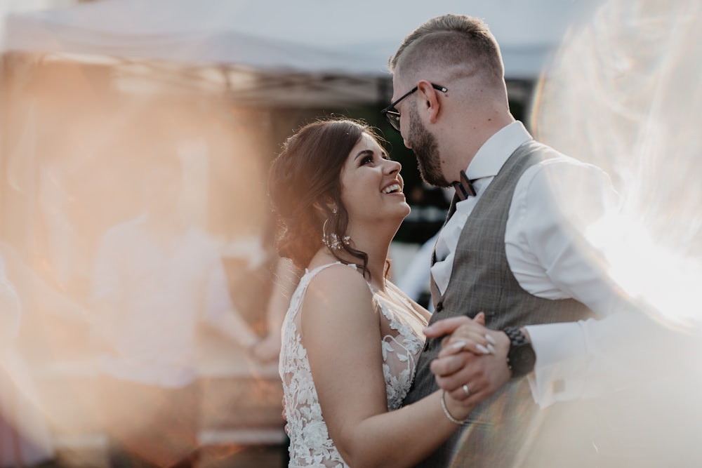 man in black suit kissing woman in white sleeveless dress