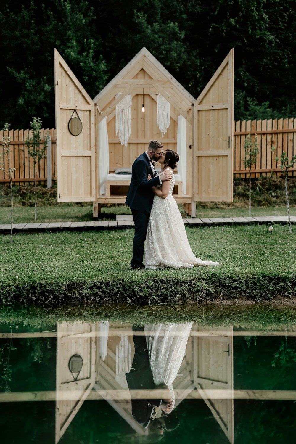 woman in white wedding gown standing beside brown wooden gate during daytime