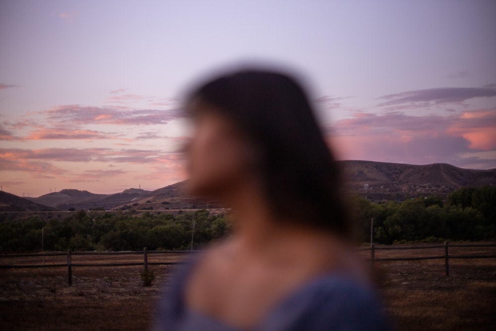 woman in blue shirt standing near green grass field during daytime