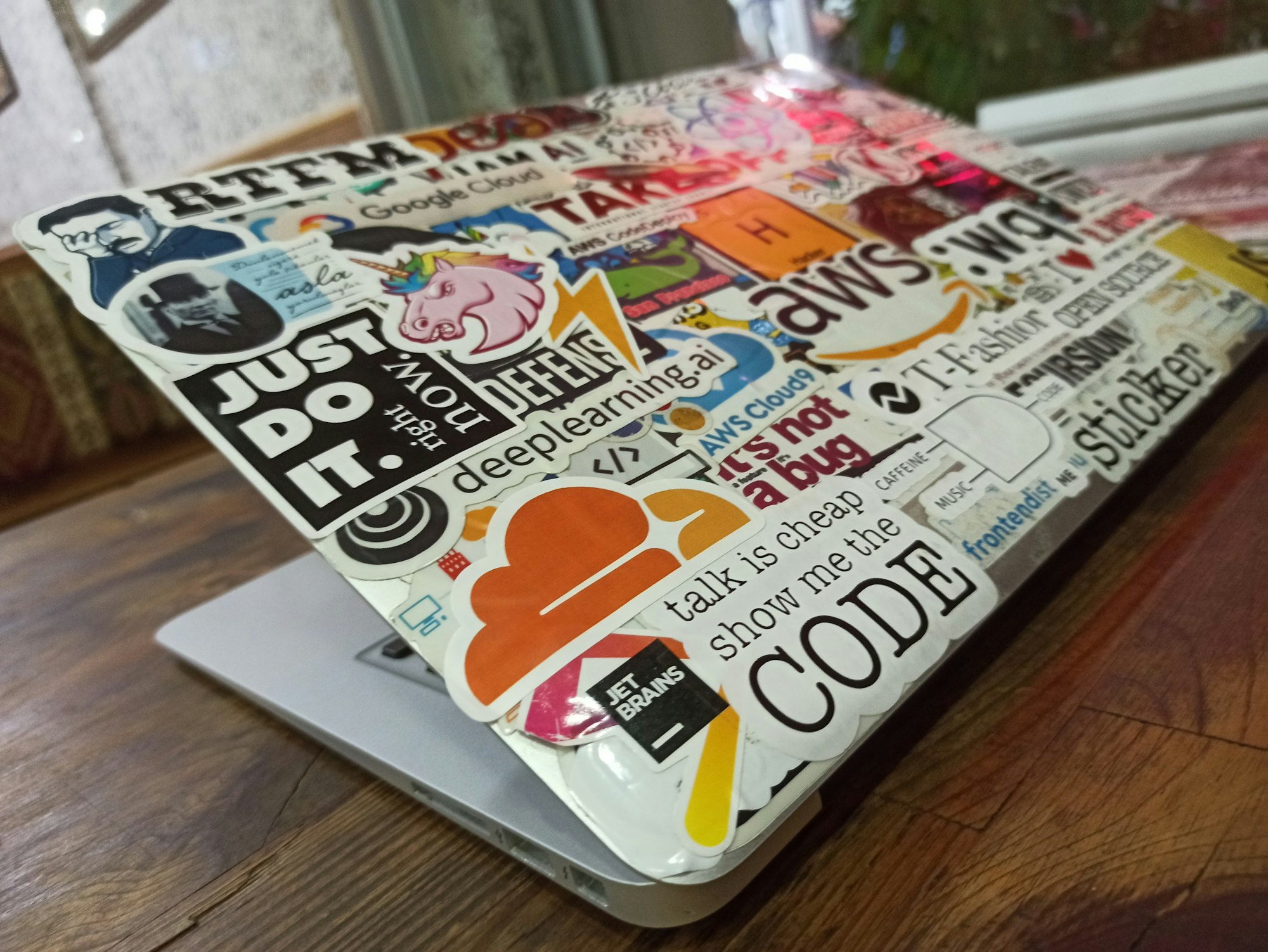 a MacBook Air with a lot of stickers about programming on the back.

talk is cheap show me the code
just do it right now
open source
:wq
aws
jetbrains
cloudflare
rtfm 
unicorn
t-fashion
